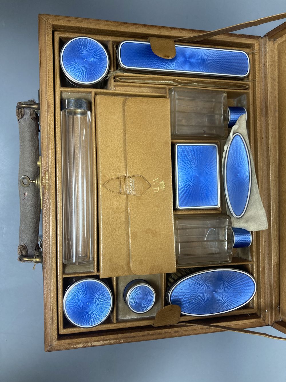 A late 19th/early 20th century French ten piece white metal and blue guilloche enamel travelling toilet set in leather case,